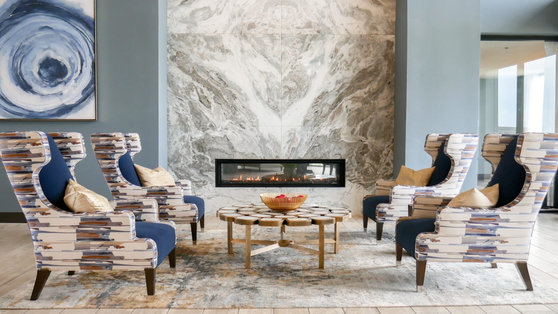 a living room with blue chairs and a marble fireplace at The Terra at University North Park
